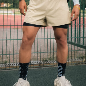 Man wearing khaki shorts and black socks standing on a tennis court.