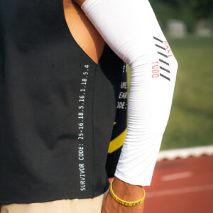 Athlete's arm sleeve with motivational text near a sports track.